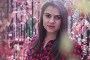 portrait of a young beautiful girl sitting in a forest. Smiling happy woman looking at camera. Autumn Walk