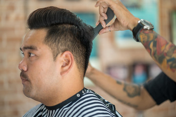The male barber is cutting the male customer in the barber shop