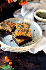 Chocolate pumpkin brownie on a plate on a dark wooden background, still life