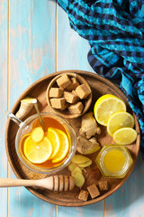 Cup of hot tea with lemon, ginger, honeycomb and honey on a wooden table. Top view on a flat background. Copy space.