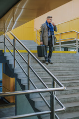 Elegant man holding travel suitcase and drinking coffee