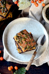 Chocolate pumpkin brownie on a plate on a dark wooden background, still life