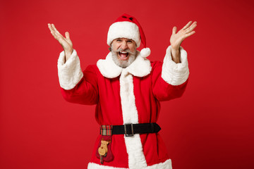Fototapeta na wymiar Crazy elderly gray-haired mustache bearded Santa man in Christmas hat posing isolated on red background. Happy New Year 2020 celebration holiday concept. Mock up copy space. Screaming spreading hands.
