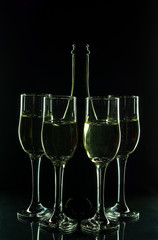 Champagne bottle, four glasses of champagne on a black background