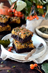Chocolate pumpkin brownie on a plate on a dark wooden background, still life