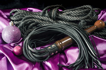 bdsm still life black leather whip rope shibari and christmas ball on pink cloth