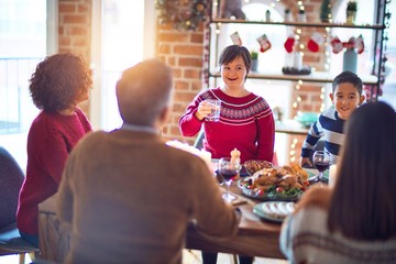 Beautiful family smiling happy and confident. One of them standing holding cup of water speaking speech celebrating christmas at home