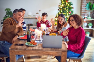 Beautiful family smiling happy and confident. Eating roasted turkey make videocall using laptop celebrating christmas at home