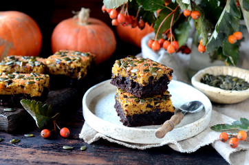 Chocolate pumpkin brownie on a plate on a dark wooden background, still life