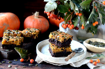 Chocolate pumpkin brownie on a plate on a dark wooden background, still life