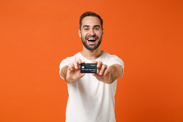 Laughing young man in casual white t-shirt posing isolated on bright orange wall background studio...