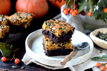Chocolate pumpkin brownie on a plate on a dark wooden background, still life