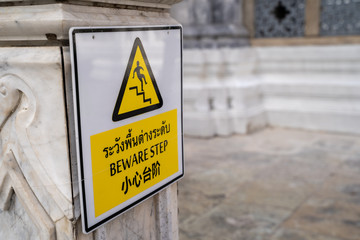 Sign at the Grand Palace Bangkok Thailand - English translation from Thai - Beware Step - tells visitors to watch their step