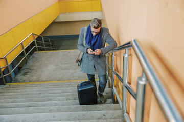 Elegant man standing on steps and using mobile phone