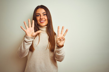 Young beautiful woman wearing winter turtleneck sweater over isolated white background showing and pointing up with fingers number eight while smiling confident and happy.