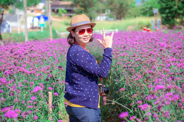 Asian women in Verbena bonariensis flower field with blue sky backgroud. Purple flower vintage, blurred and soft background.