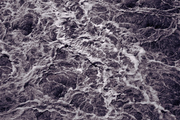 Abstract background, rough water surface. Foaming water, black and white. Foam and bubbles. Stormy waves. Splendor, magnificence and power of nature concept. Foam pattern. Monochrome