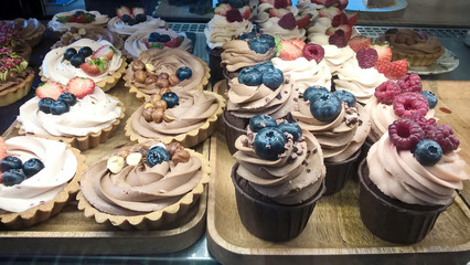 Cakes on Display in Cake Shop. Lots of Fruitcakes and Cupcakes in Showcase of Pastry Shop. Different Sweets for Sale