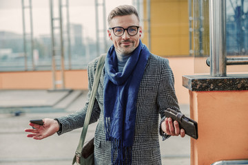 Confused handsome man holding cellphone and wallet