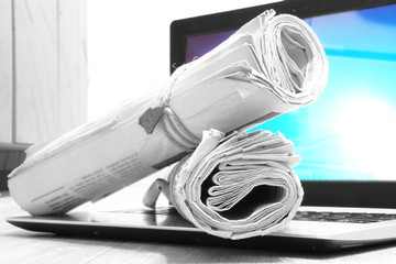 Newspapers and Laptop. Two Rolled Magazines and Computer with Blue Screen. Tabloid Journals and Open Notebook. Business and News Concept  