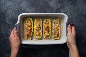Baked stuffed zucchini boats with minced chicken mushrooms and vegetables with cheese on a baking sheet. Top view Copy space