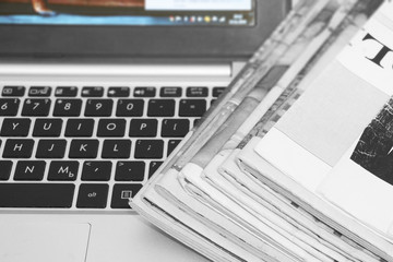 Newspapers and laptop. Pile of daily papers with news on the computer. Pages with headlines,...