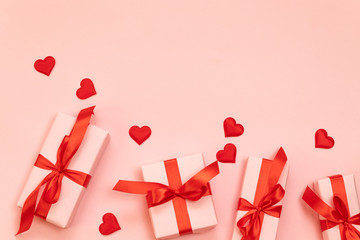 Valentine's day composition with surprise gifts with red bow and heart shape on a pink background with copyspace