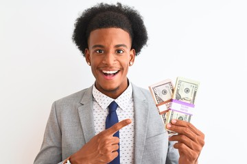 Young african american businessman holding dollars standing over isolated white background very happy pointing with hand and finger