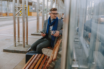 Fototapeta na wymiar Handsome elegant man sitting on bench outdoors