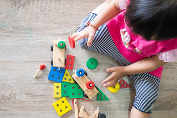 Body​ part of​ baby​ girl​ playing​ the​ wooden​ block toys.​ On​ wooden​ floor.​ 1-2​ years​ old​ of​ child.​ Learning​ and​ development​ of​ kid​ concept