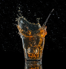 Glasses of whiskey with splash, isolated on black background
