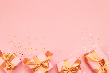 Valentine's day composition or banner with surprise gifts with gold bow on a pink background. Flat lay, top view, copy space.
