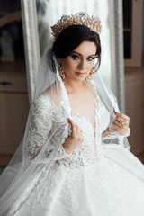 Bride's fees. The bride plays with a veil. Bride with elegant hairstyle with crown and makeup. Wedding. Beautiful happy bride preparing for her wedding. Happiest bridal day.