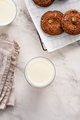 Closeup top view of a cup with milk, a chocolate cookie on white background.
