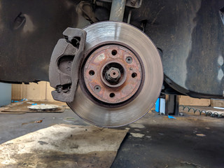 Closeup of metallic disk of a car without tires ready to have a new rubber tire after a problem while driving, coming for help and assistance in a mechanics shop