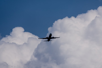 in the background of blue sky and white cumulus clouds in the distance approaching aircraft