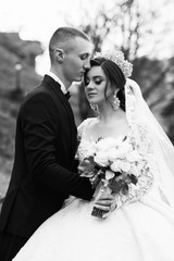 The groom gently kisses the bride. Autumn wedding. Bride with a beautiful bouquet. Young wedding...
