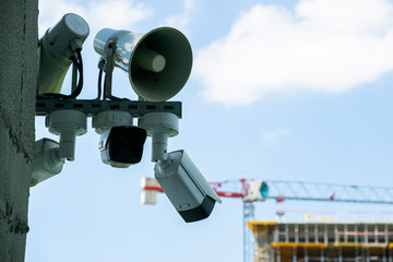CCTV cameras and loudspeakers on a wall of a building. There is building under construction in...
