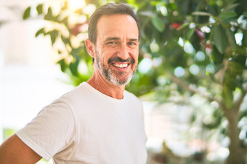 Middle age handsome man wearing casual t-shirt standing on terrace smiling