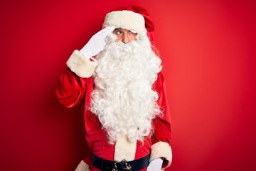 Middle age handsome man wearing Santa costume standing over isolated red background Shooting and killing oneself pointing hand and fingers to head like gun, suicide gesture.