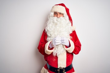 Middle age handsome man wearing Santa costume standing over isolated white background Hands together and fingers crossed smiling relaxed and cheerful. Success and optimistic