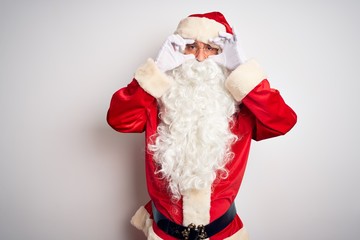 Middle age handsome man wearing Santa costume standing over isolated white background Trying to open eyes with fingers, sleepy and tired for morning fatigue