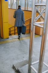 Stylish gentleman carrying travel suitcase and heading to stairs