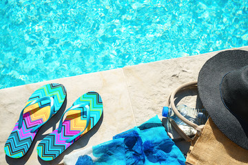 Swimming pool and straw hat, colorful flip flops, wicker bag, straw hat, bottle with still water as...