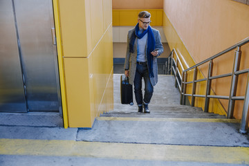 Handsome man walking up the stairs and using cellphone