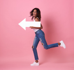 Portrait of shocked young african woman jumping with her arrow pointing at copy space isolated over...