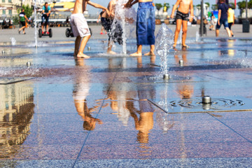 Children splashing in the city fountain. Hot summer day.