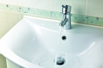 Water flows from the faucet into the sink. Concept saving water.