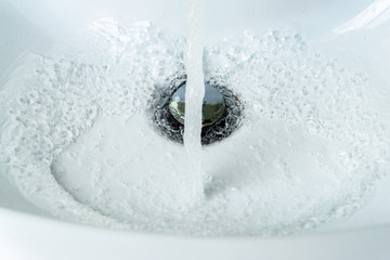 Water flows from the faucet into the sink. Concept saving water.