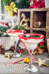 Christmas cocktail recipe. Winter alcohol beverage, White Christmas martini or daiquiri, On wooden background with xmas decoration and peppermint candy cane